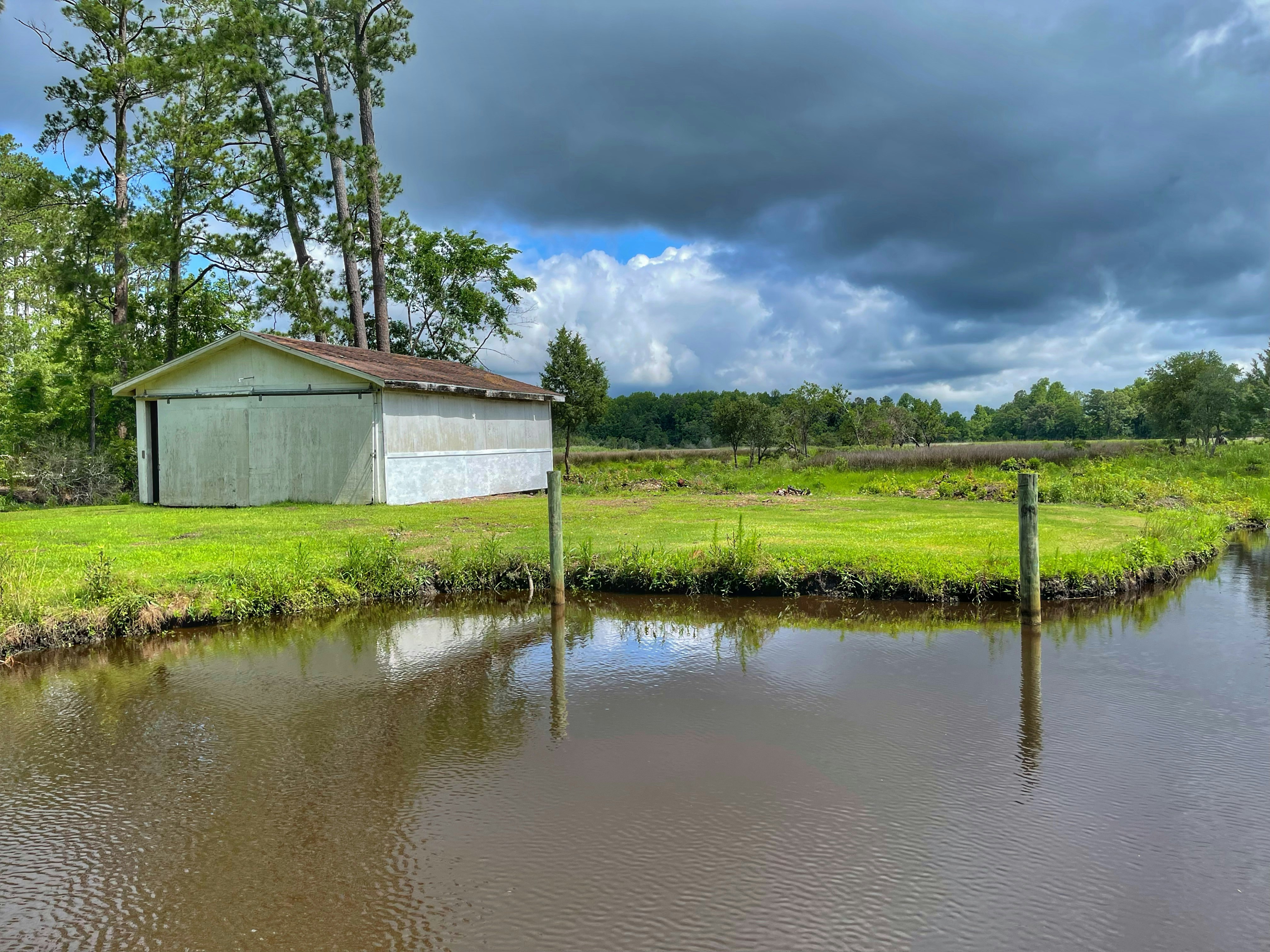 white wooden house beside green grass field and body of water during daytime